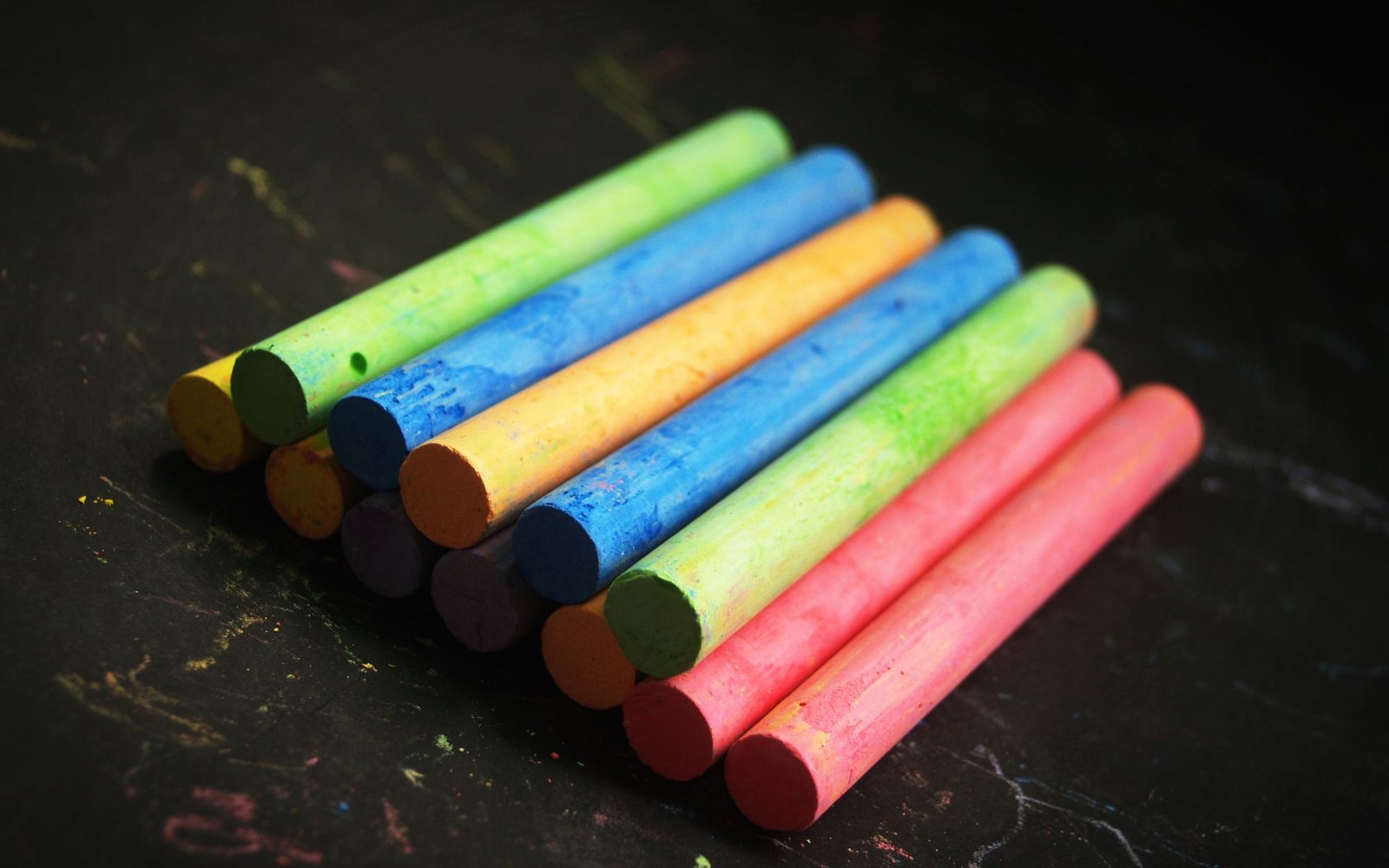 Coloured chalk sticks arranged on a slate surface